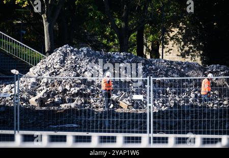 Dresda, Germania. 15 ottobre 2024. I lavoratori si trovano sul lato della città Vecchia dell'Elba di fronte ai detriti del ponte di Carolabrücke crollato. La sezione occidentale del ponte con i binari del tram, la pista ciclabile e il sentiero è crollata nella notte dell'11 settembre 2024 per ragioni sconosciute. Crediti: Robert Michael/dpa/Alamy Live News Foto Stock