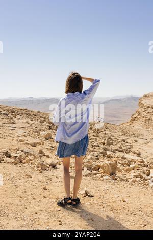 Una donna sta sola nel vasto deserto, guardando le montagne lontane Foto Stock