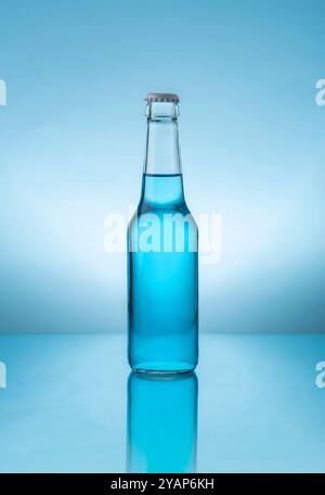 Flacone in vetro con tappo contenente liquido blu su superficie blu riflettente su sfondo blu Foto Stock