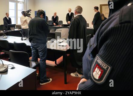 Amburgo, Germania. 15 ottobre 2024. Un uomo di 34 anni accusato di omicidio e incendio doloso particolarmente grave (centro l) e il suo avvocato Fabian Hellweg (centro r) aspettano in aula l'inizio del processo. Si dice che l'accusato abbia pugnalato la vittima diverse volte nella zona testa e collo con un coltello. L'attacco ha portato alla morte dell'uomo. In seguito, si dice che l'accusato abbia dato fuoco all'appartamento per coprire il crimine. Crediti: Ulrich Perrey/dpa/Alamy Live News Foto Stock