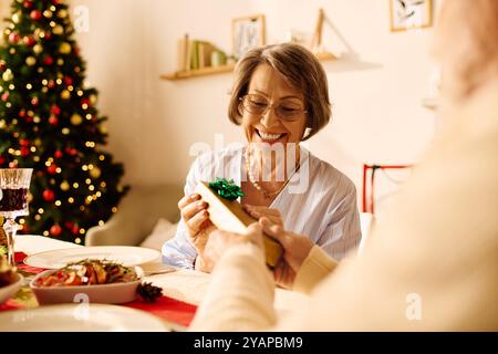 Una coppia di anziani felice gode del calore del Natale, scambiandosi regali e felicità a casa. Foto Stock