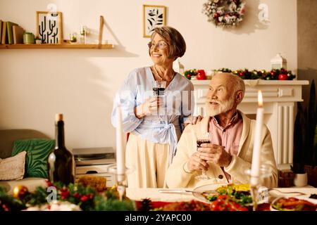 Una coppia senior condivide un felice momento natalizio a casa, godendosi la compagnia degli altri. Foto Stock