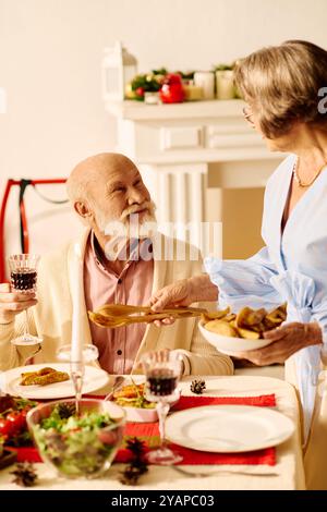 Una coppia senior condivide risate e amore mentre si prepara per la cena di Natale a casa. Foto Stock