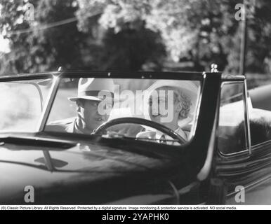 Negli anni '1930 L'attore Adolf Jahr sul sedile del passeggero di un'auto guidata da una giovane donna bionda durante la registrazione di un film. Una cabriolet con cofano abbassato nelle giornate di sole. Foto Stock