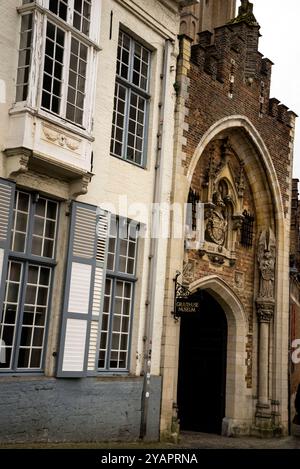 Portale gotico con merlature e fessure a freccia a Bruges, Belgio. Foto Stock