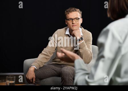 Un giornalista si impegna in un dialogo profondo con uno specialista, esplorando argomenti importanti in un elegante studio. Foto Stock