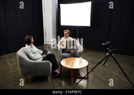 Un giornalista di mezza età si impegna in una discussione approfondita con uno specialista, condividendo le proprie competenze. Foto Stock