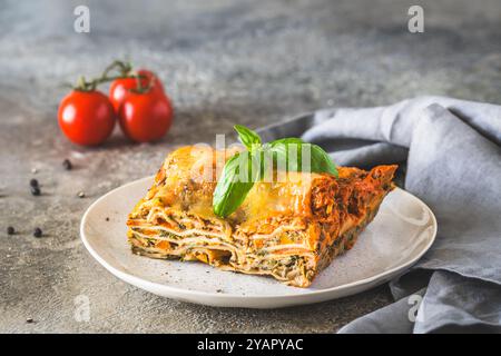 Lasagne italiane con salsa di pomodoro, spinaci e formaggio, sfondo leggero in cemento. Lasagne vegetariane fatte in casa. Messa a fuoco selettiva. Foto Stock