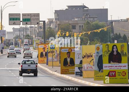 Duhok, Iraq. 13 ottobre 2024. Le auto si sono spostate oltre le bandiere elettorali per i candidati in vista delle elezioni del Parlamento regionale del Kurdistan nella città di Duhok, Iraq. (Foto di Ismael Adnan/SOPA Images/Sipa USA) credito: SIPA USA/Alamy Live News Foto Stock