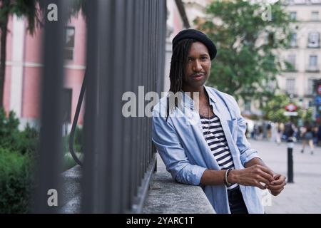 ritratto di un giovane uomo alla moda che guarda la fotocamera con dreadlock e un berretto Foto Stock