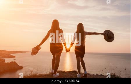 Silhouette di due donne che si tengono per mano al tramonto Foto Stock