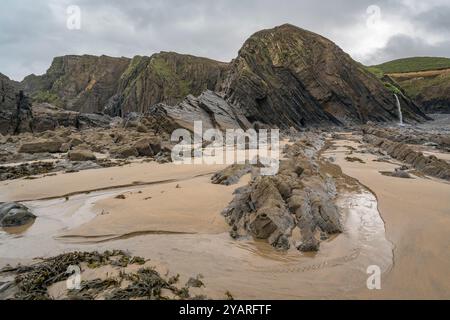 Scogliere, sabbia e piscine rocciose sulla spiaggia di Sandymouth Foto Stock