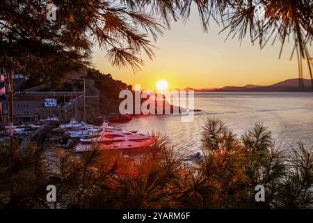 Incredibile tramonto arancione sulle isole greche (vista dall'isola di Idra) - vista dall'isola di Idra (porto), sulla terraferma della Grecia in lontananza. (Accanto al pino Foto Stock