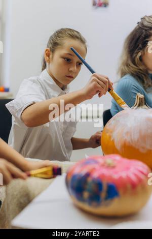 Bambini e adulti dipingono le zucche per Halloween, divertendosi e divertendosi insieme. Foto di alta qualità Foto Stock