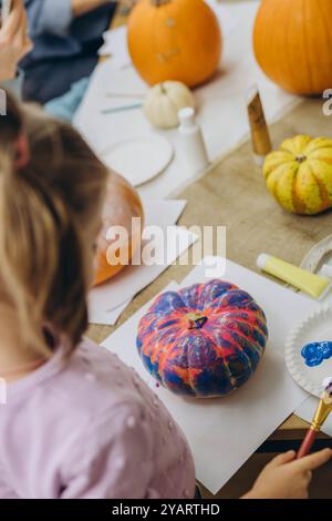 Bambini e adulti dipingono le zucche per Halloween, divertendosi e divertendosi insieme. Foto di alta qualità Foto Stock