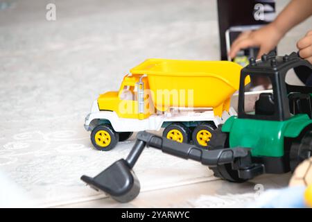 Attrezzature per la costruzione di giocattoli colorati in plastica. Ragazzo senza volto che gioca con camion e apripista. Infanzia. Foto orizzontale. Gente, bambino, ragazzo. Foto Stock