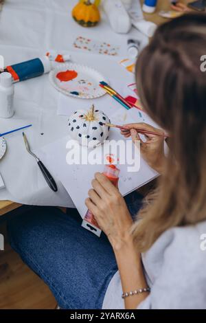 Bambini e adulti dipingono le zucche per Halloween, divertendosi e divertendosi insieme. Foto di alta qualità Foto Stock