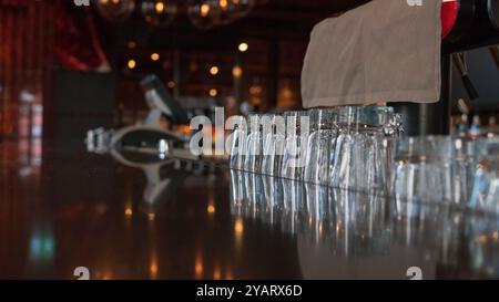 Bicchieri da shot vuoti di fila su un bancone di un bar all'interno di un nightclub. Fila di bicchieri da bibita collocati al bancone del bar. Foto Stock