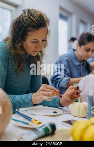 Bambini e adulti dipingono le zucche per Halloween, divertendosi e divertendosi insieme. Foto di alta qualità Foto Stock