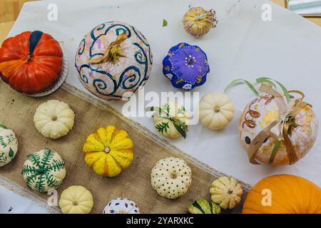 Bambini e adulti dipingono le zucche per Halloween, divertendosi e divertendosi insieme. Foto di alta qualità Foto Stock