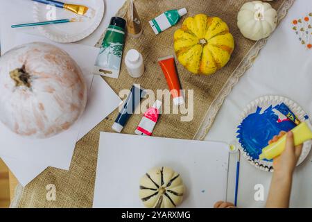 Bambini e adulti dipingono le zucche per Halloween, divertendosi e divertendosi insieme. Foto di alta qualità Foto Stock