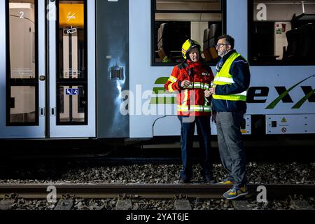 Namborn, Germania. 15 ottobre 2024. Dirk Schäfer (l), ispettore dei vigili del fuoco distrettuale e ministro degli interni della Saarland Reinhold Jost (SPD) si trovano accanto a un treno espresso regionale gestito da vlexx. Il treno regionale si era scontrato con un grande masso sui binari e deragliò sul binario aperto. Credito: Laszlo Pinter/dpa/Alamy Live News Foto Stock