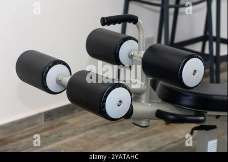 Questo ambiente dispone di un'attrezzatura da palestra versatile progettata per gli esercizi della parte inferiore del corpo, con rulli imbottiti e una struttura elegante. Ideale per Foto Stock