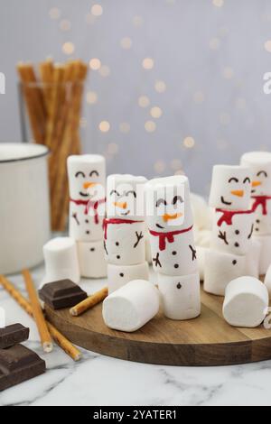 Simpatici pupazzi di neve realizzati con marshmallow su un tavolo di marmo bianco Foto Stock