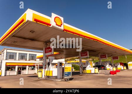 Wasserbillig, Lussemburgo - 29 luglio 2024: Una stazione di servizio Shell ben illuminata dispone di diverse pompe di rifornimento sotto un cielo azzurro, che mostrano il carburante corrente Foto Stock