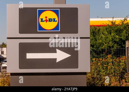 Wasserbillig, Lussemburgo - 29 luglio 2024: Un cartello mostra in primo piano un logo e punta a destra, indirizzando i clienti al negozio LIDL locale. Il luminoso Foto Stock