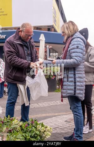 Neuwied, Germania - 12 ottobre 2024: Al mercato del giardino locale una cliente donna paga a un venditore maschile per le piante acquistate. L'atmosfera è vivace, Foto Stock