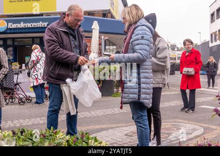 Neuwied, Germania - 12 ottobre 2024: Al mercato del giardino locale una cliente donna paga a un venditore maschile per le piante acquistate. L'atmosfera è vivace, Foto Stock