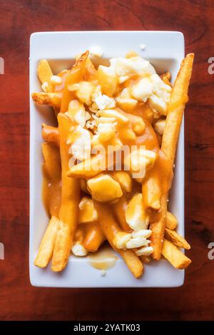 Piatto di poutine con patatine croccanti condite con cagliate di formaggio e ricco sugo bruno Foto Stock