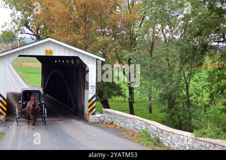 Un calesse Amish attraversa un ponte coperto nella contea di Lancaster, Pennsylvania Foto Stock