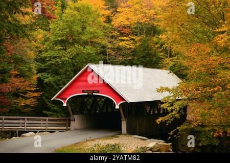 Un pittoresco ponte coperto è circondato da un brillante fogliame autunnale in una giornata autunnale nel New England Foto Stock