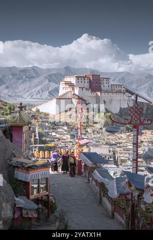 SHIGATSE, TIBET - 1 AGOSTO 2022: Ruote tibetane di preghiera o rotoli di preghiera dei fedeli buddisti e castello Shigatse, Tibet, Cina Foto Stock