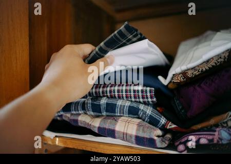 Mani che portano i vestiti all'interno di un armadio in legno Foto Stock