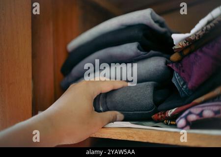 Mani che portano i vestiti all'interno di un armadio in legno Foto Stock