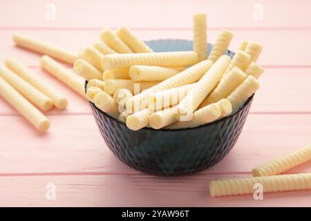 Deliziosi rotoli di wafer per il latte sul recipiente su sfondo rosa. Vista dall'alto Foto Stock