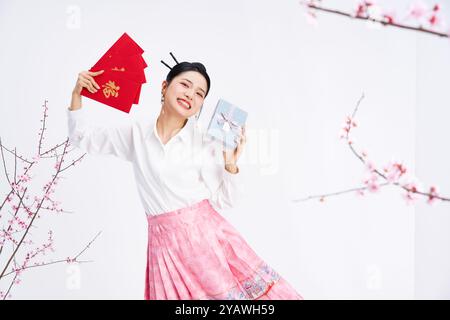 Una giovane donna cinese che tiene buste rosse e scatole regalo Foto Stock