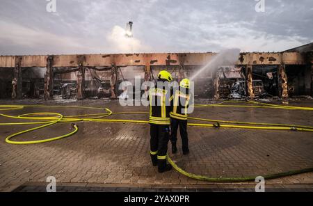 Stadtallendorf, Germania. 16 ottobre 2024. I vigili del fuoco sono in servizio davanti a un deposito veicoli. Mercoledì mattina, il deposito veicoli della stazione dei vigili del fuoco di Stadtallendorf nel quartiere Marburg-Biedenkopf è stato completamente distrutto in un grande incendio. Crediti: Nadine Weigel/dpa/Alamy Live News Foto Stock