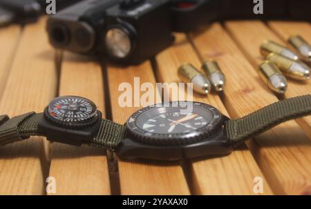 Orologio militare con bussola e pistola su tavolo di legno Foto Stock