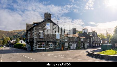 GRASMERE, CUMBRIA, REGNO UNITO - 13 SETTEMBRE 2024. Paesaggio panoramico di negozi, tra cui la libreria Sam Reed nel centro del villaggio di Grasmere, in Inghilterra Foto Stock