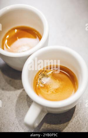 Due tazze di espresso appena preparato sul piano, con colori crema e caldi Foto Stock