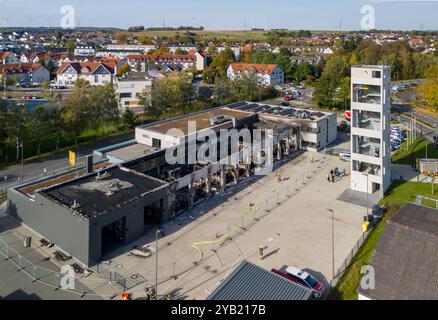 Stadtallendorf, Germania. 16 ottobre 2024. Immagine del drone i vigili del fuoco sono occupati con lavori post-estinguenti. Il nuovo deposito di attrezzature del dipartimento dei vigili del fuoco volontario di Stadtallendorf è completamente bruciato con veicoli e attrezzature, causando milioni di danni. Crediti: Andreas Arnold/dpa/Alamy Live News Foto Stock