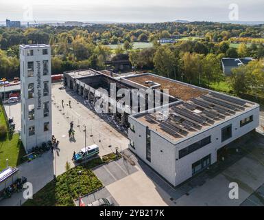 Stadtallendorf, Germania. 16 ottobre 2024. Immagine del drone i vigili del fuoco sono occupati con lavori post-estinguenti. Il nuovo deposito di attrezzature del dipartimento dei vigili del fuoco volontario di Stadtallendorf è completamente bruciato con veicoli e attrezzature, causando milioni di danni. Crediti: Andreas Arnold/dpa/Alamy Live News Foto Stock