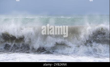 L'oceano è ruvido e le onde si schiantano contro la costa. Il cielo è nuvoloso e l'acqua è di colore blu intenso Foto Stock