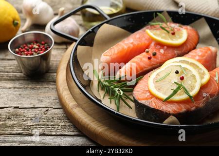 Bistecche di salmone crude fresche con spezie in padella su tavola di legno, primo piano Foto Stock