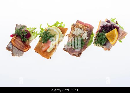 Salato smørrebrød danese con insalata di carne, pâté e bacon su rugbrød. Un classico sandwich a vista, perfetto per un pasto abbondante. Foto Stock