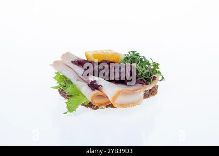 Salato smørrebrød danese con insalata di carne, pâté e bacon su rugbrød. Un classico sandwich a vista, perfetto per un pasto abbondante. Foto Stock